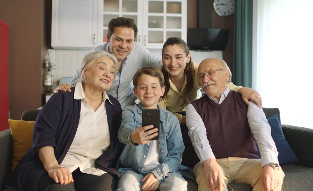 Family sitting on the sofa smiling at a smartphone